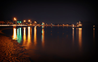Fototapeta na wymiar Night lights on the seashore. city skyline. big city lights at the beach. reflected in water