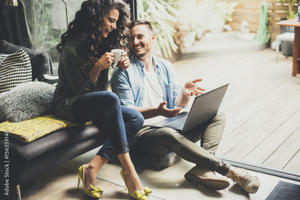 Wall mural happy cute couple in love with laptop drinking coffee and smiling