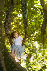 Naklejka premium outdoor portrait of young child girl in magic forest, swinging outdoors on natural background