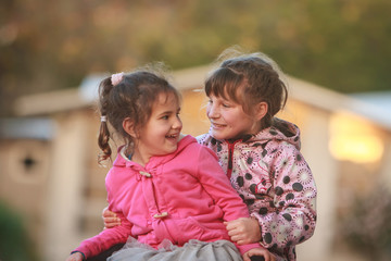 Fototapeta premium outdoor portrait of two young happy children, girls - sisters - playing in park on natural background