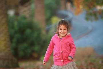 outdoor portrait of young happy child girl playing in park on natural background