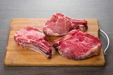 Raw Bone-in Rib eye Steak on wooden background
