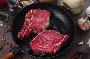 Raw fresh meat rib eye steak composition in grill pan on wooden background