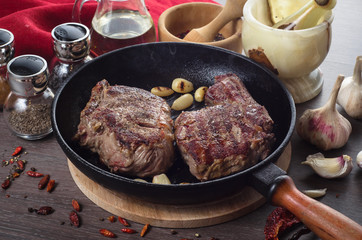 Grilled rib eye steak composition on grill iron pan on wooden background