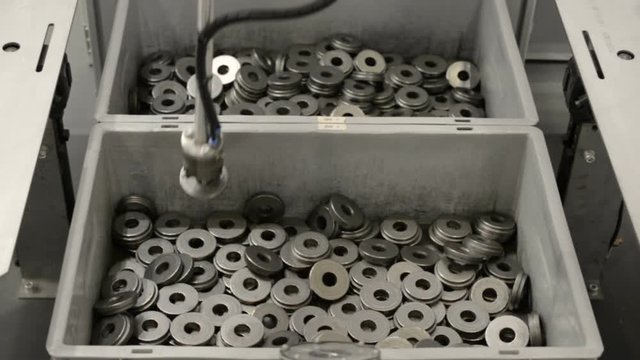 The robot manipulator takes the metal spacers out of the box and checks them with the sample.