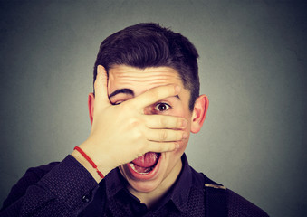 man looking surprised in disbelief, with hand on face looking at camera