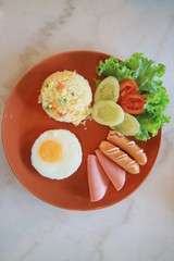 American style breakfast set American fried rice topped sunny up egg pea corn fried  sausage fried and slice tomato and cucumber.