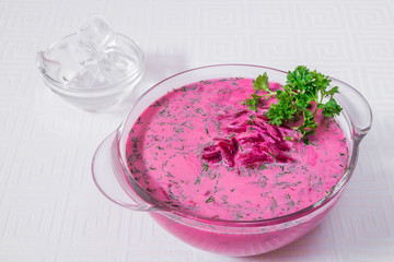 Delicious, appetizing pink soup with beets and herbs in a white plate. Horizontal frame
