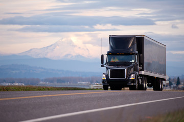 Stylish black modern powerful truck with black trailer scenic road © vit
