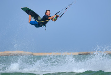 Fototapeta premium Professional kitesurfing rider sportsman jumps high acrobatics kiteboarding backroll trick with huge water splash. Recreational activity and extreme active water sports, hobby and fun in summer time