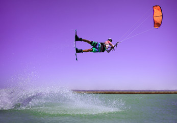 Professional kite boarding rider sportsman jumps high acrobatics kiteboarding raley trick  with huge water splash. Recreational activity and extreme active water sports, hobby and fun in summer time