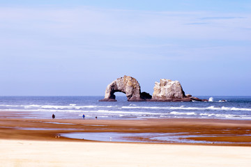 Delightful nice panorama of Pacific coast with sand and lazy wave with two towering cliffs