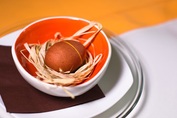 Easter egg on the straw in colored plate and tablecloth