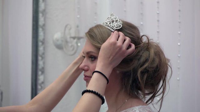 Bridesmaid helped the future bride to choose wedding dress. Young woman preparing for wedding