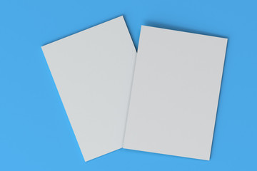 Two blank white closed brochure mock-up on blue background