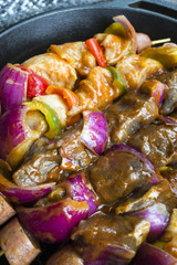 Skewers of meat sausage and vegetables in frying pan