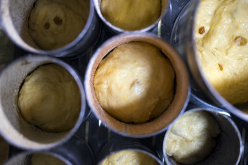 The dough with raisins in round cans growing before baking