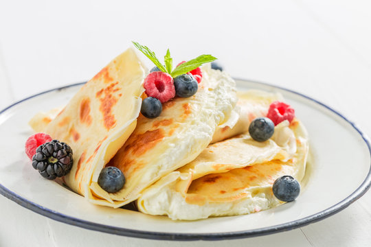 Sweet pancakes with curd and berries and powder sugar