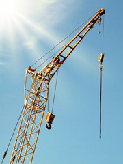 mobile crane boom against blue sky under sunlight, toned