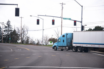 Blue semi truck and trailer on road with traffic lights