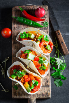 Hot tacos with spicy sauce and fresh coriander
