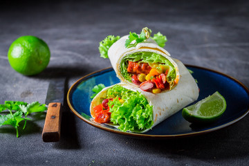 Burrito with red salsa, lettuce and vegetables