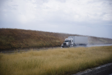 Semi truck rig with trailer on road in rain dust