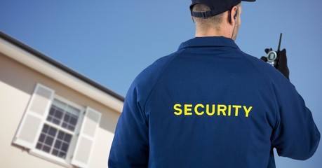 Obraz premium Security man in front of a house holding a talkie-walkie