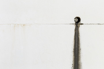 Dirt from the drain on white cement wall, outdoor day light