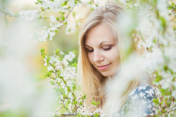 Beautiful, lovely and young woman at the flowers of tree branches in spring.