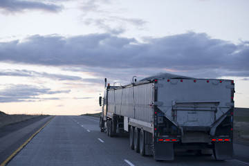 Semi truck with long bulk trailer on evening road