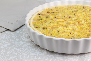 Creamy quiche with cheese, bacon and mushroom - Open pie in white dish with selective focus - food background with text space