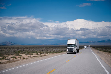 Semi trucks convoy on straight road in Nevada prairie