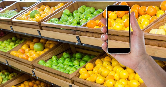 Hand taking picture of fruits with smart phone in grocery shop