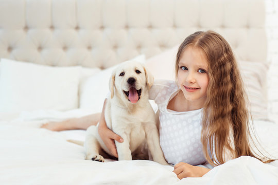 Girl on the bed with labrador puppy