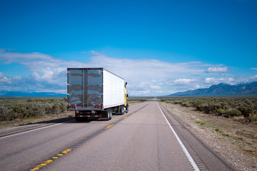 Yellow semi truck drive with commercial cargo by Nevada road