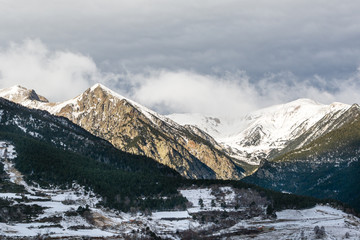 Winter Pyrenees landscape: icy mountain peaks, lightened with bright sun and rocky terrace in shadows. Pyrenees, Spain