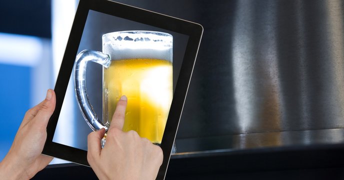 Hand taking picture of beer glass through digital tablet