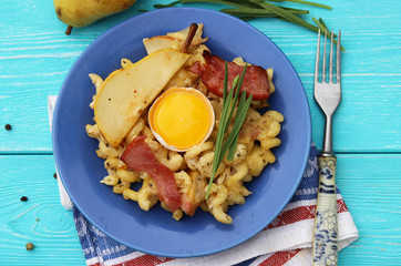 Pasta with pear, bacon and rosemary on a blue background.