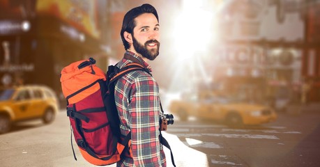 Hipster carrying backpack with camera and travelling in city