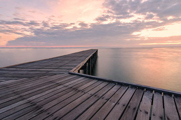 Naklejka na ściany i meble Wooden bridge at the sea at sunset