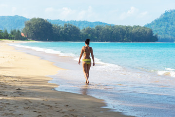 woman enjoy on the beach by standing on the sand with light swell of the sea approach touching to legs