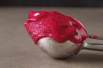 Spoon ice cream with red sorbet lies on a gray table. Space for text.