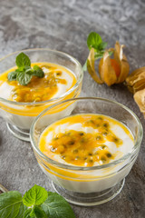 Yogurt with trapicheskim fruit, passionfruit and winter cherry in a glass vase on stone background