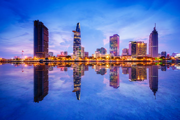 Fototapeta na wymiar Cityscape in reflection of Ho Chi Minh city at beautiful twilight, viewed over Saigon river. Hochiminh city is the largest city in Vietnam with population around 10 million people