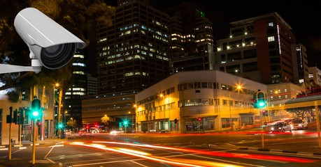 Fototapeta premium CCTV camera against light trails in city at night