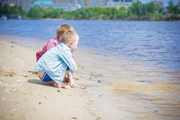 Kids boys playing on a beach near river with water and sand felling happy