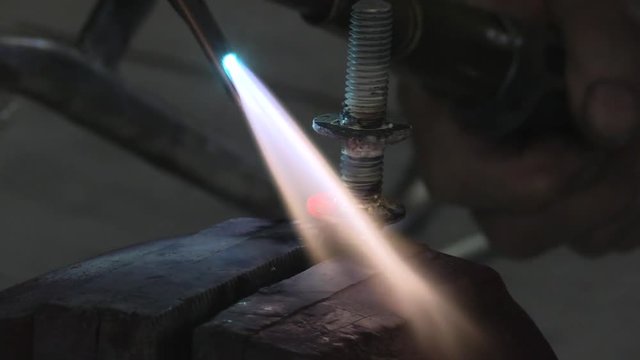 Close up of welding joining metal parts with hot flame using filler.

