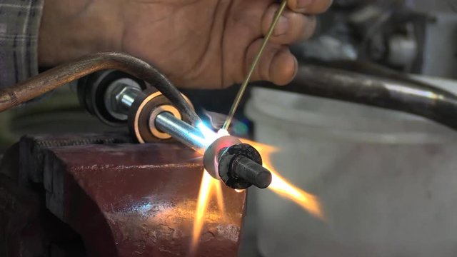Close up of welding joining metal parts with hot flame using filler.
