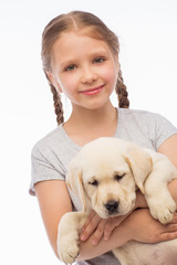 Little girl with labrador puppy, on a gray background
